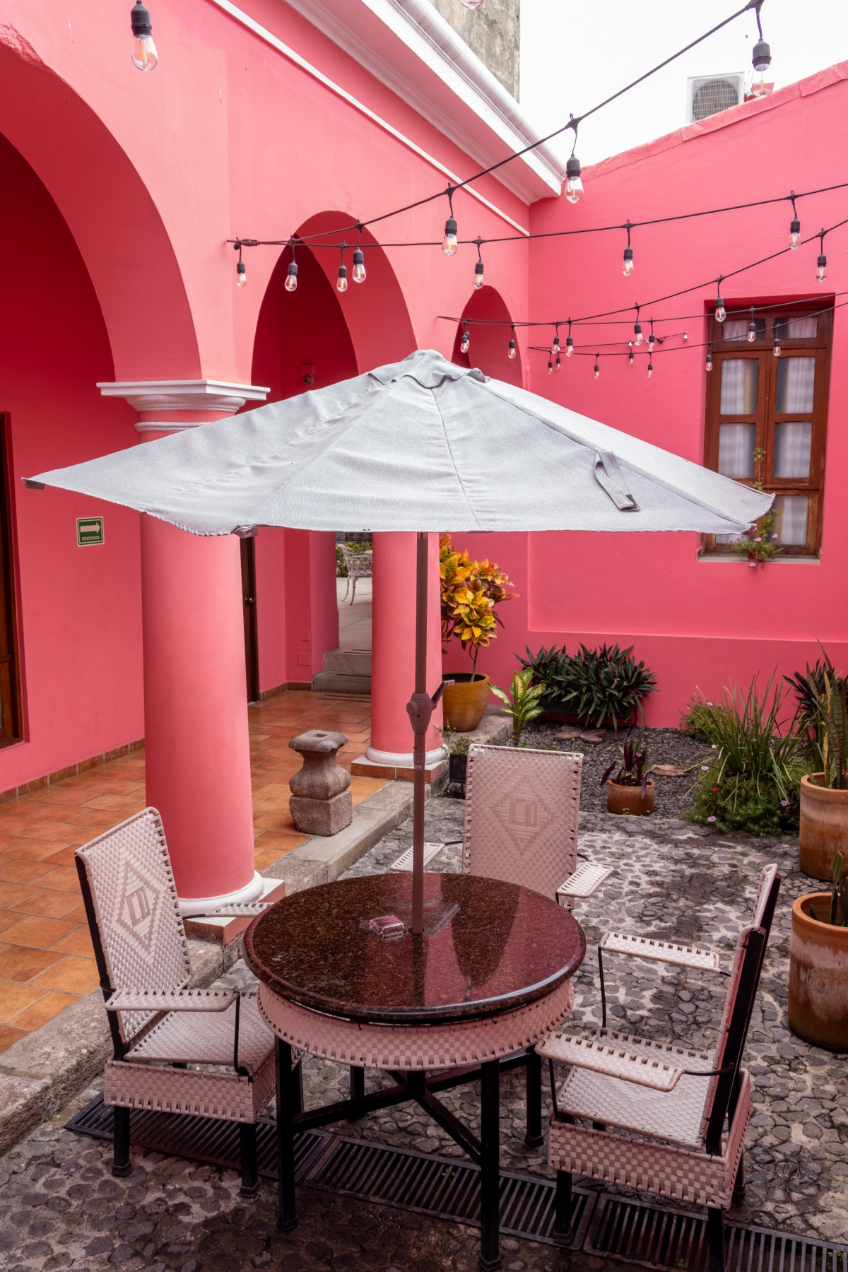 Patio interior del Hotel Casa Danna al atardecer, con arcos rosas, columnas y luces cálidas